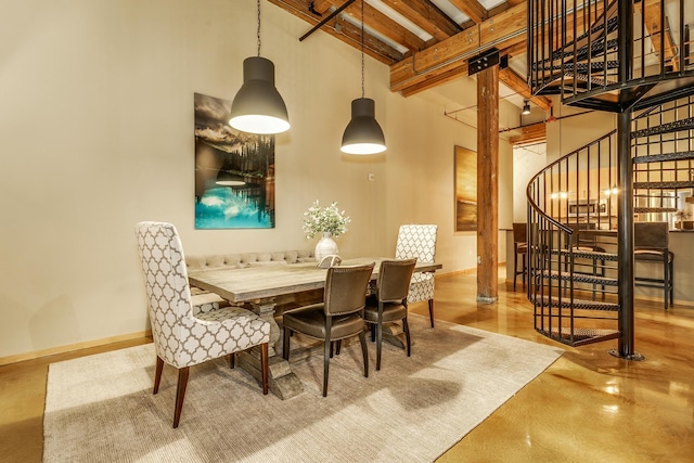 dining area with beamed ceiling, a towering ceiling, and concrete flooring