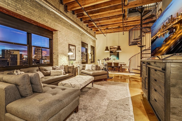 interior space with hardwood / wood-style flooring, beamed ceiling, brick wall, and a high ceiling