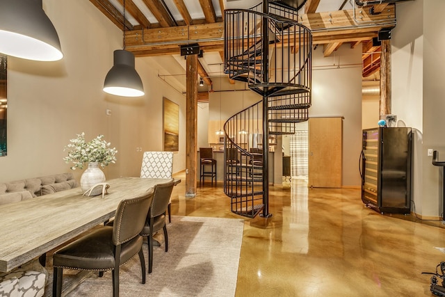 dining room with beam ceiling and a towering ceiling