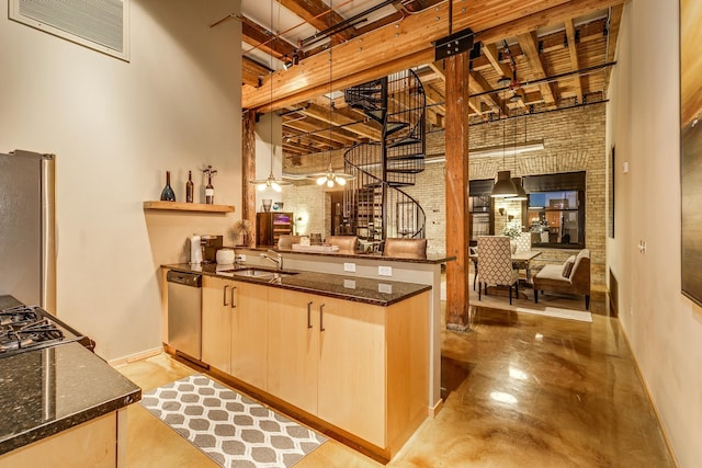 bar with sink, dark stone countertops, hanging light fixtures, a high ceiling, and stainless steel appliances