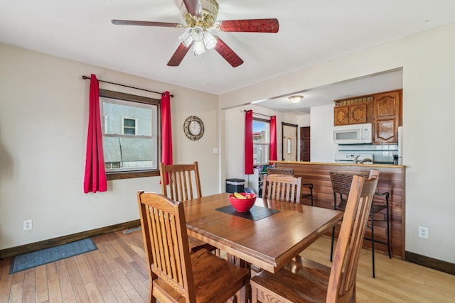 dining space featuring light wood-style flooring, baseboards, and ceiling fan