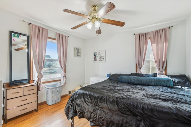 bedroom featuring light wood-style flooring, baseboards, visible vents, and ceiling fan