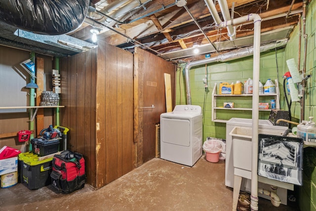 unfinished below grade area featuring concrete block wall, independent washer and dryer, and a sink