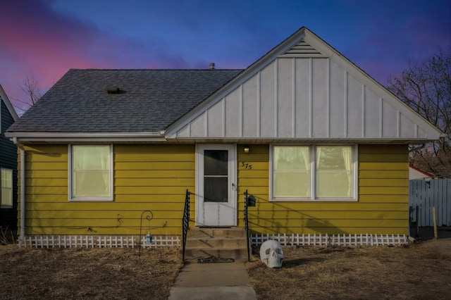 bungalow-style home featuring fence, roof with shingles, entry steps, crawl space, and board and batten siding