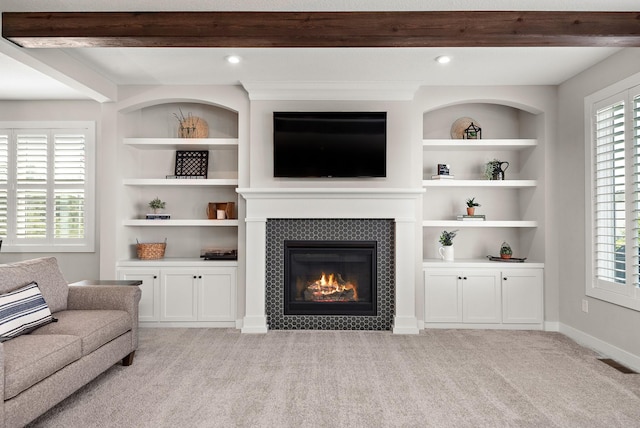 unfurnished living room featuring plenty of natural light, light carpet, beam ceiling, and built in shelves