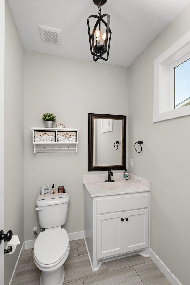 bathroom with vanity, toilet, and an inviting chandelier