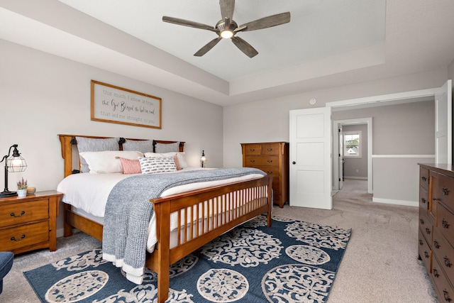 carpeted bedroom featuring a raised ceiling and ceiling fan