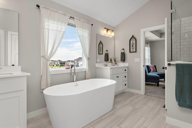 bathroom featuring lofted ceiling, a healthy amount of sunlight, vanity, and a washtub