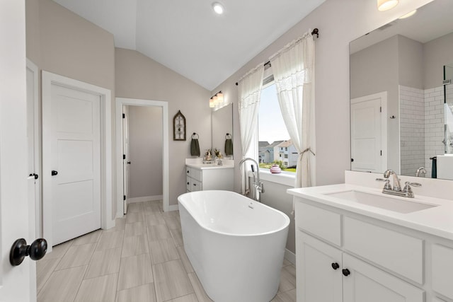 bathroom featuring vanity, lofted ceiling, and a bathtub