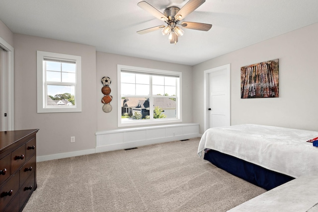 bedroom featuring ceiling fan, light colored carpet, and multiple windows