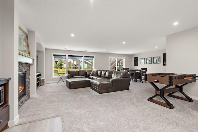 living room with a stone fireplace and light colored carpet