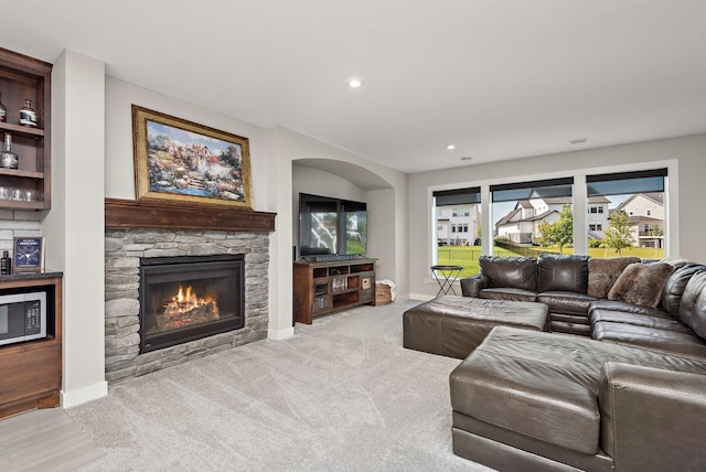 living room with light colored carpet and a stone fireplace