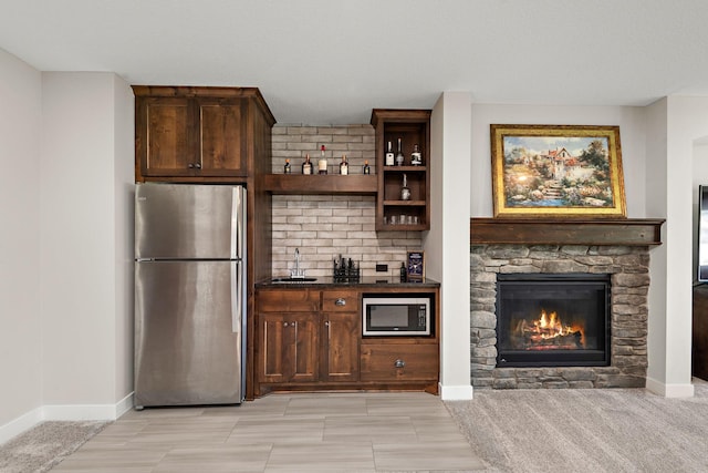 bar with sink, stainless steel fridge, a fireplace, built in microwave, and decorative backsplash