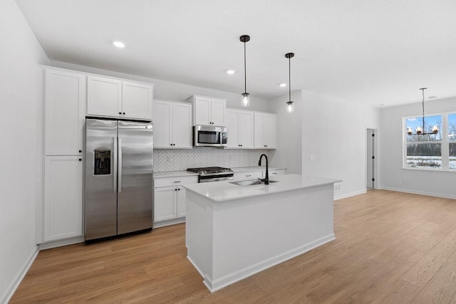 kitchen featuring light wood-style floors, tasteful backsplash, appliances with stainless steel finishes, and a sink