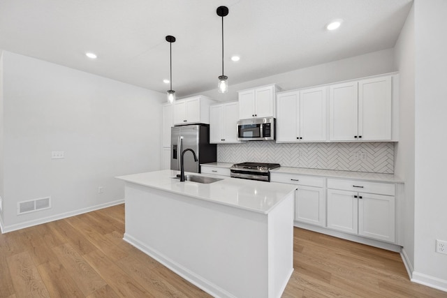 kitchen featuring a center island with sink, visible vents, a sink, appliances with stainless steel finishes, and white cabinetry