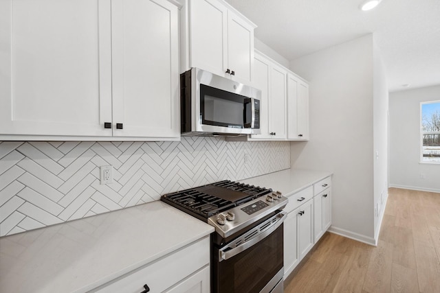 kitchen featuring white cabinetry, backsplash, appliances with stainless steel finishes, and light countertops