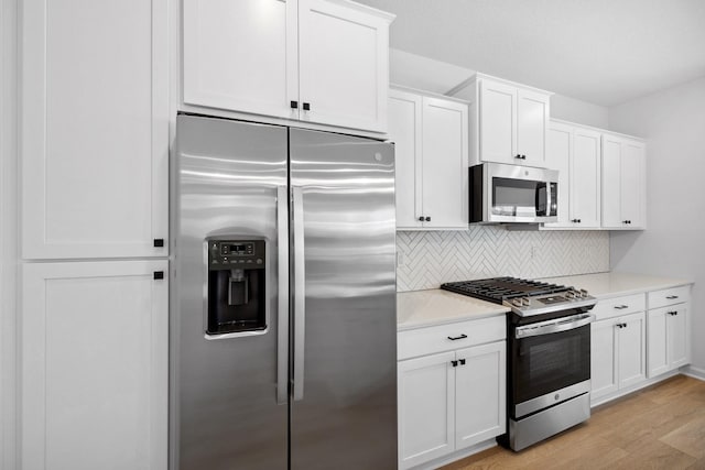 kitchen with light countertops, white cabinets, light wood-type flooring, and appliances with stainless steel finishes