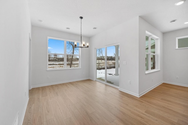 unfurnished dining area with light wood-type flooring, baseboards, and a chandelier