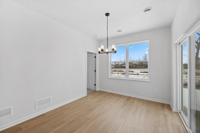 unfurnished dining area featuring light wood-style flooring, a notable chandelier, visible vents, and plenty of natural light