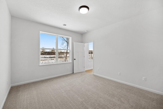 carpeted spare room featuring baseboards and a textured ceiling