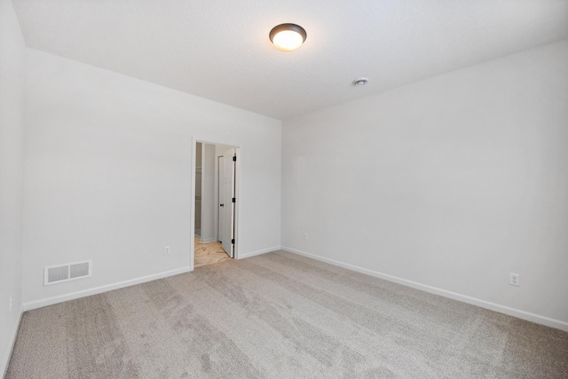 empty room with visible vents, light colored carpet, and baseboards