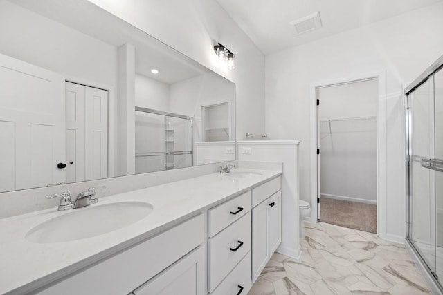 bathroom with a shower stall, double vanity, marble finish floor, and a sink