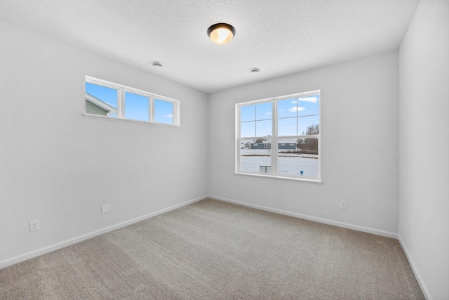 carpeted spare room with baseboards and a textured ceiling