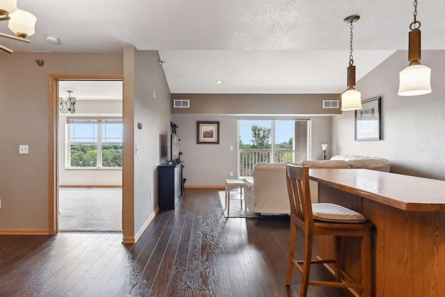 kitchen with hanging light fixtures, plenty of natural light, dark wood-type flooring, and a textured ceiling