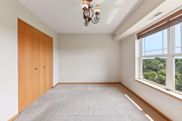 carpeted empty room with a chandelier