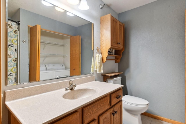 bathroom featuring tile patterned floors, vanity, toilet, and washing machine and dryer