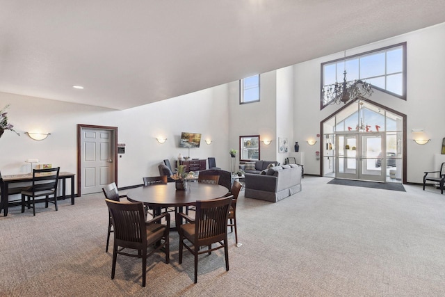 dining area with light carpet, a towering ceiling, and french doors