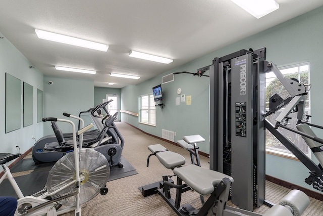 exercise room with a textured ceiling and carpet flooring