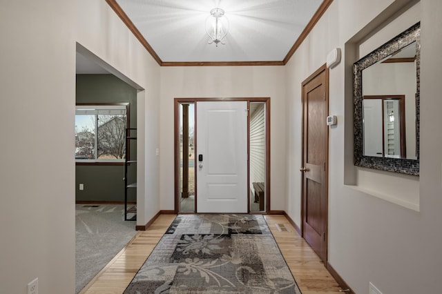 entrance foyer with light wood-style floors, crown molding, and baseboards