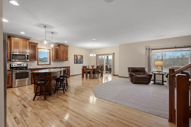 kitchen featuring a breakfast bar, a kitchen island, open floor plan, appliances with stainless steel finishes, and light wood finished floors