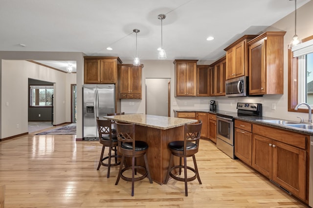 kitchen featuring stainless steel appliances, brown cabinets, a sink, and a kitchen breakfast bar