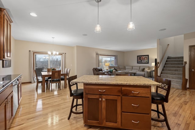 kitchen with a healthy amount of sunlight, light wood finished floors, a breakfast bar area, and brown cabinetry