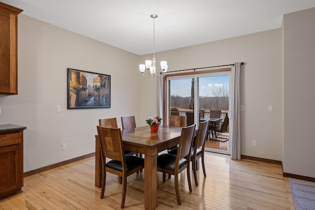 dining space with light wood finished floors, baseboards, and a notable chandelier