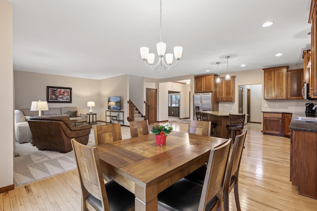 dining space featuring stairs, light wood finished floors, a chandelier, and recessed lighting