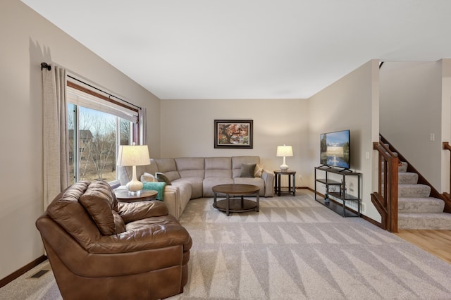 living area with light carpet, visible vents, stairway, and baseboards