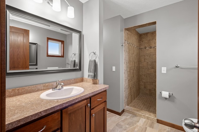 bathroom featuring a stall shower, baseboards, and vanity