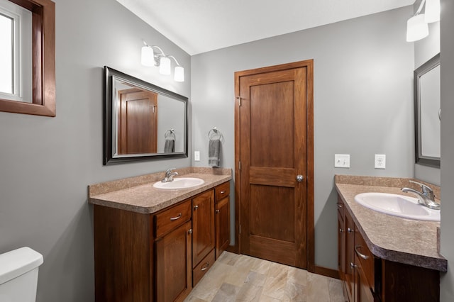 bathroom with two vanities, a sink, and toilet