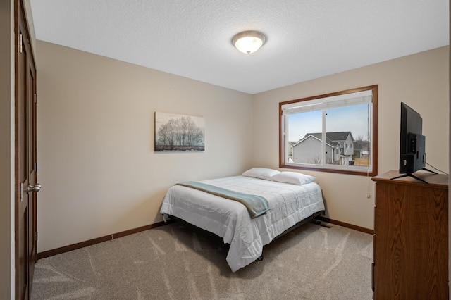 carpeted bedroom with a textured ceiling and baseboards