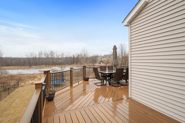 deck with outdoor dining area, a water view, and fence