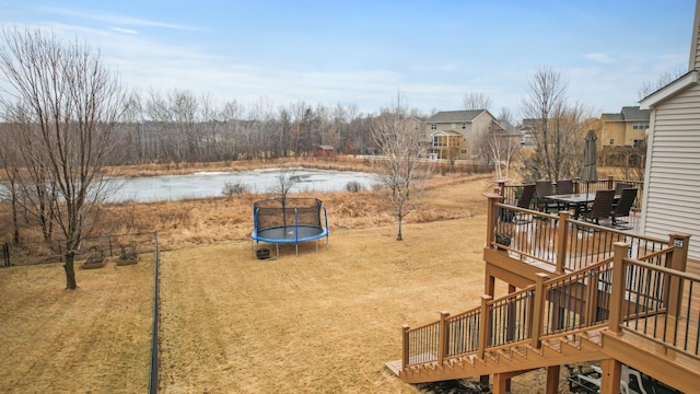 view of yard with a deck, outdoor dining space, and a trampoline