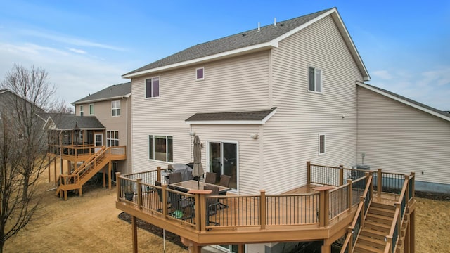 rear view of property featuring a deck, a shingled roof, and stairway