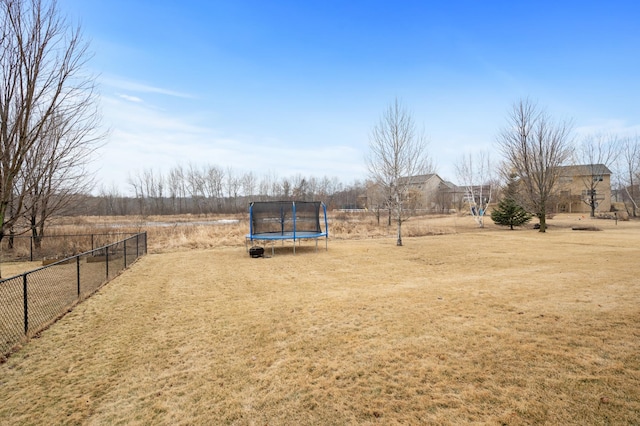 view of yard featuring a trampoline and fence