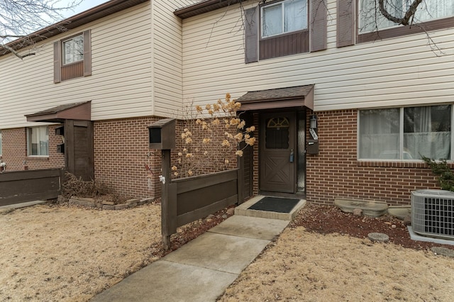 entrance to property with brick siding and central AC unit