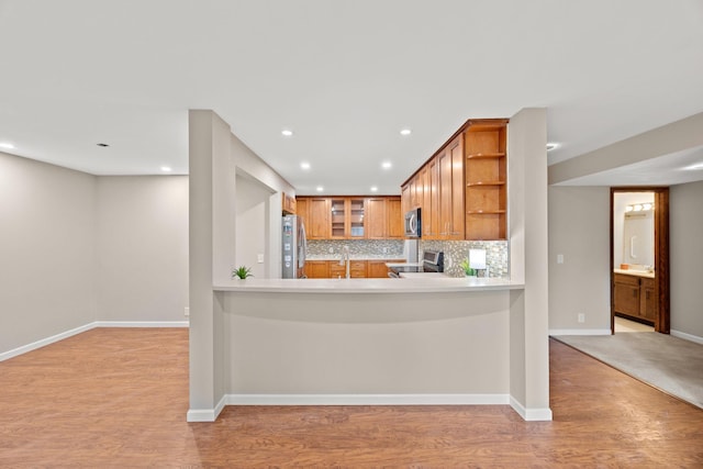 kitchen with open shelves, stainless steel appliances, decorative backsplash, light countertops, and light wood-type flooring