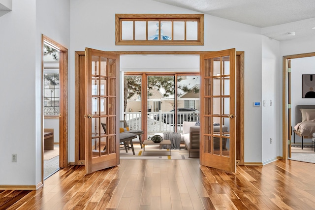 doorway to outside with hardwood / wood-style floors and high vaulted ceiling