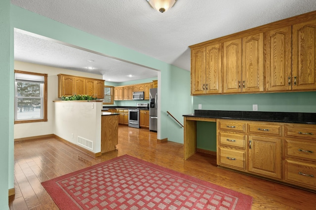 kitchen with stainless steel appliances, hardwood / wood-style floors, and a textured ceiling